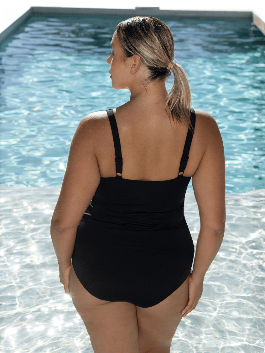 Woman standing in pool wearing a chlorine resistant tankin top with adjustable straps