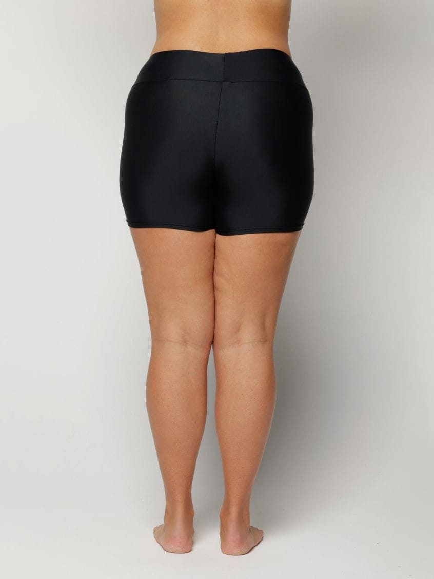 Woman wearing black high-waisted shorts on a plain background