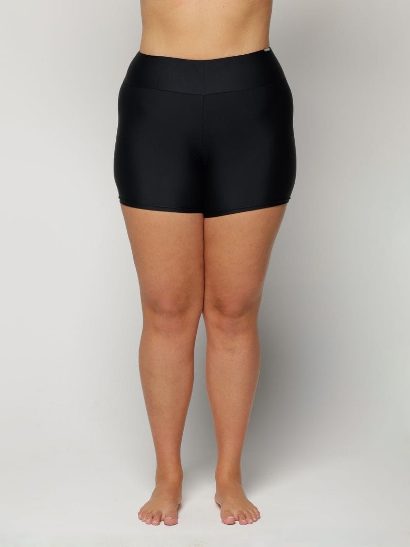 Woman wearing black high-waisted shorts on a plain background