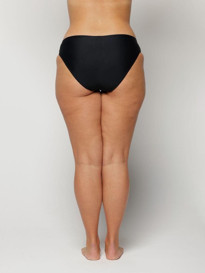 Woman wearing black underwear on a plain background