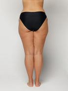 Woman wearing black underwear on a plain background