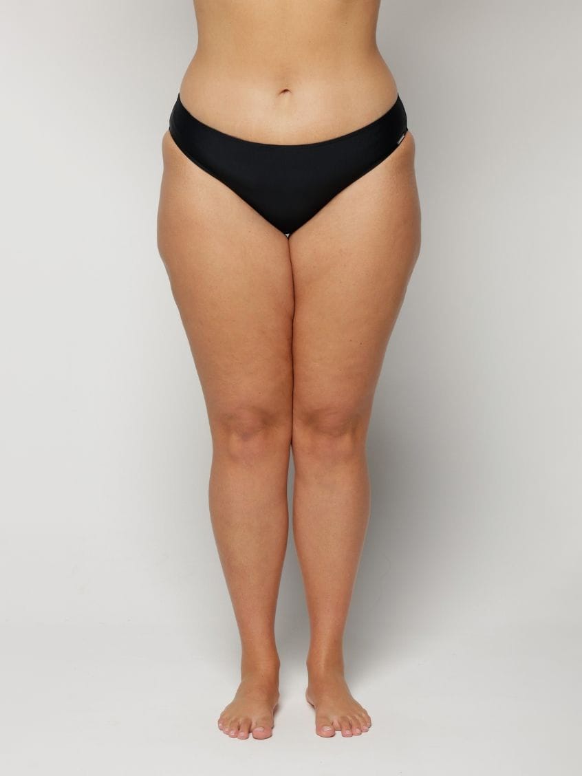 Person wearing black underwear on a plain background