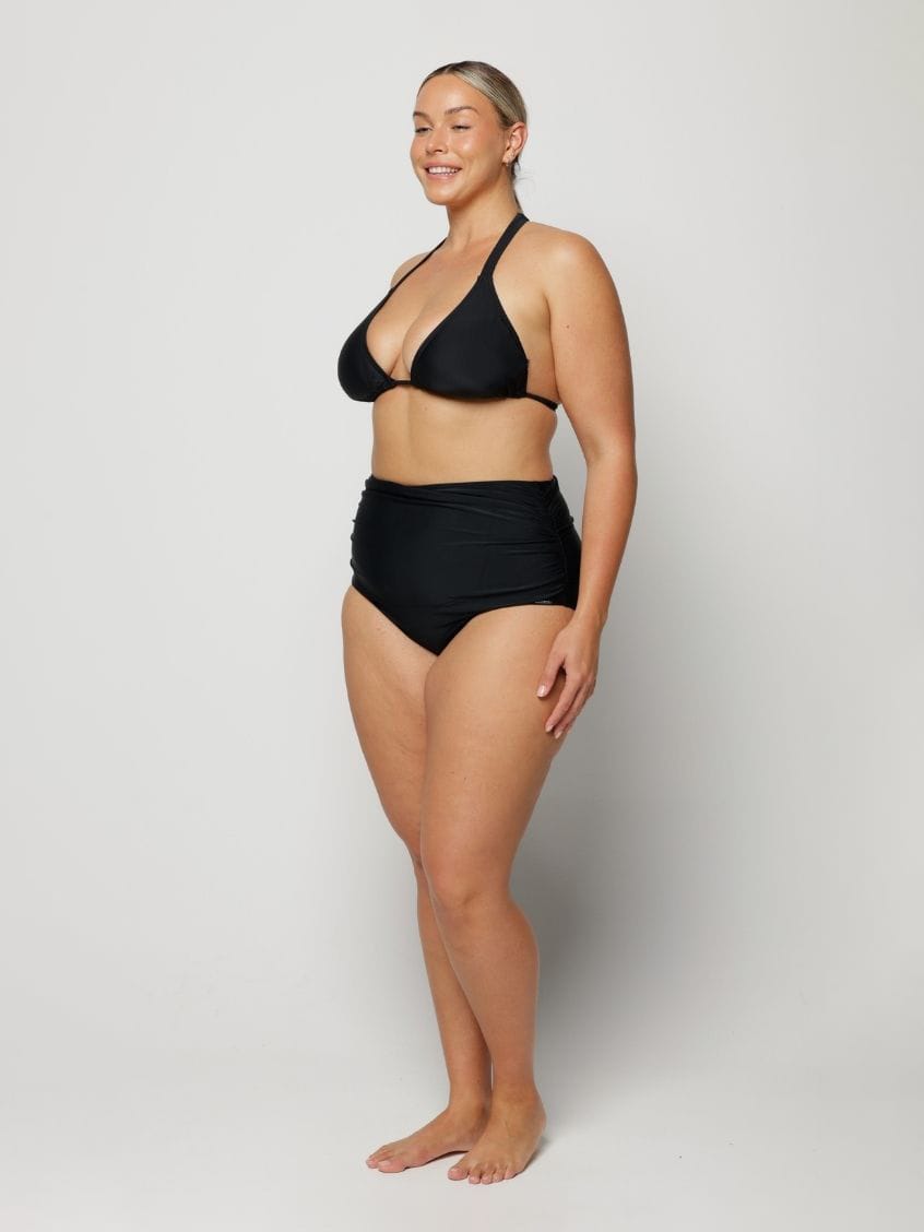 Woman wearing a black bikini on a plain background