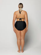 Woman wearing a black bikini on a plain background