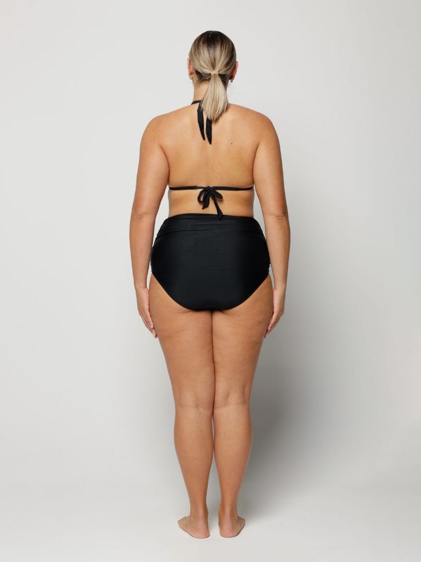 Woman wearing a black bikini on a plain background