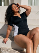Close up image of model wearing a zip front detail one piece in black and white textured print
