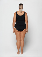 Person wearing a blue and black chlorine resistant swimsuit on a white background with high back