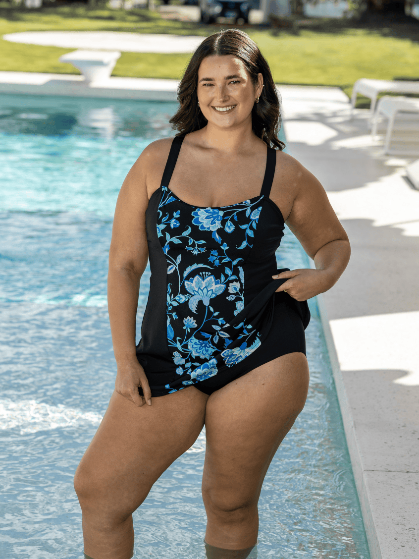 Woman wearing a black floral swim dress in chlorine resistant with built in pant