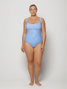 Woman wearing a blue square neck swimsuit against a white background