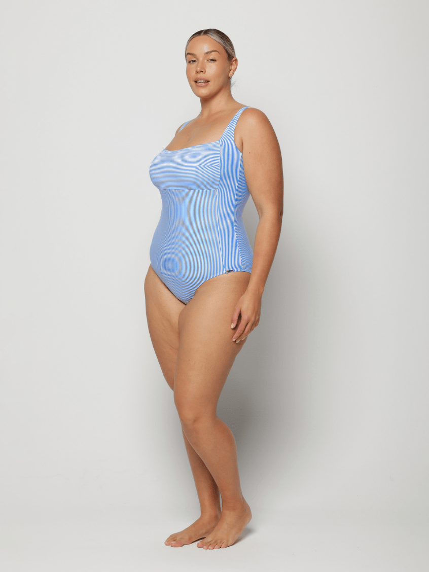Woman wearing a light blue square neck swimsuit against a white background with adjustable straps