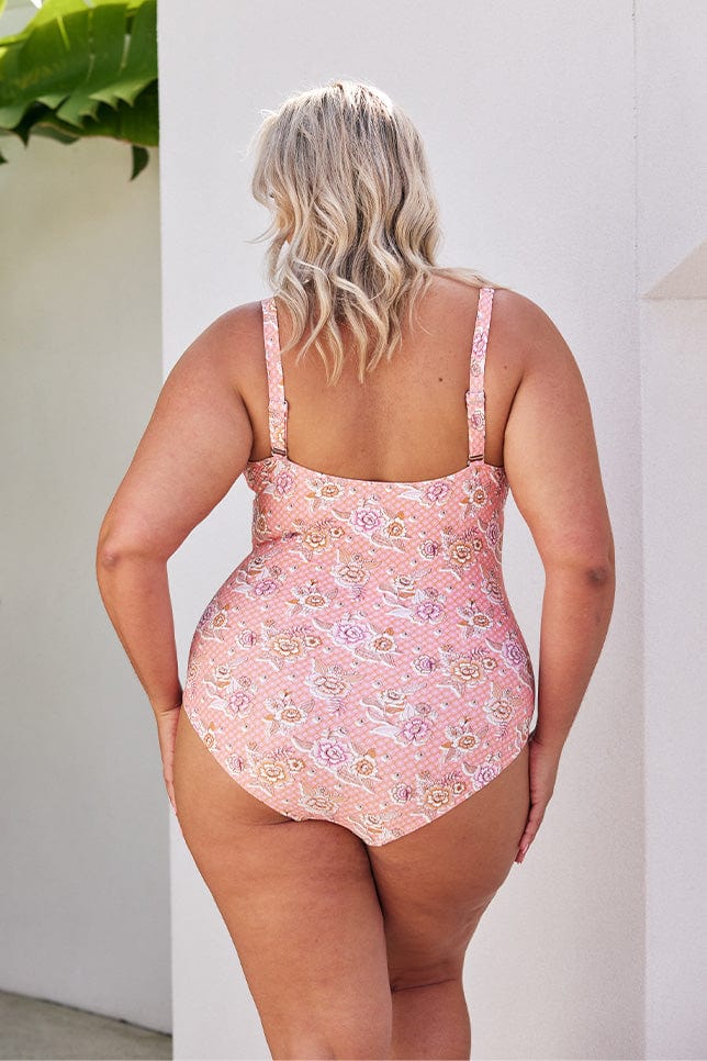 Blonde model showing back of light pink floral one piece with adjustable straps