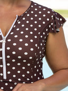 Brown polka dot top with white zipper on a blurred background