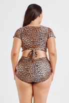 Person wearing a leopard print two-piece swimsuit on a white background
