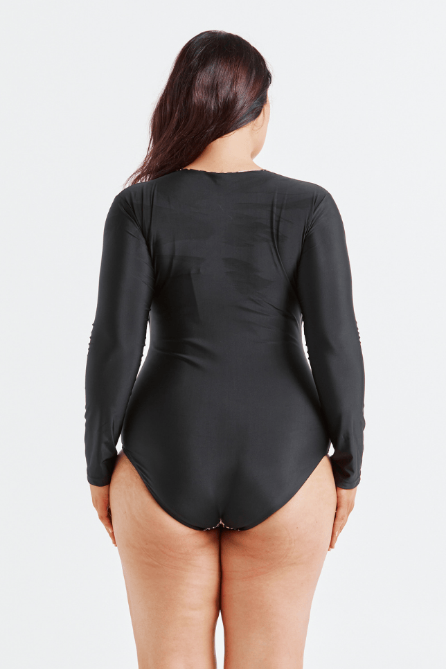 Person wearing a black long-sleeve swimsuit on a white background