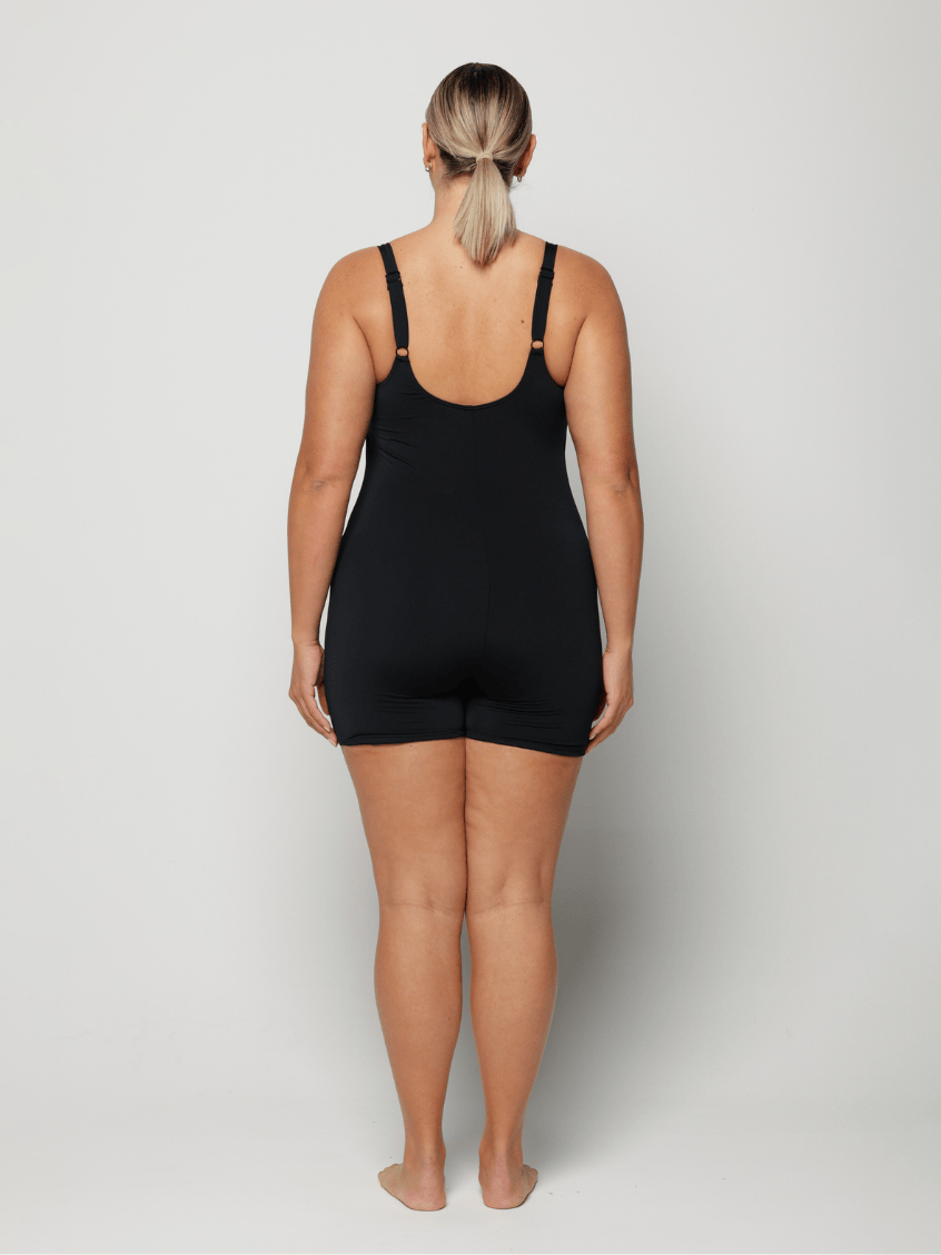 Person wearing a black boyleg one peice on a white background