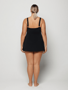 Person wearing a black and blue floral slip swim dress on a plain background