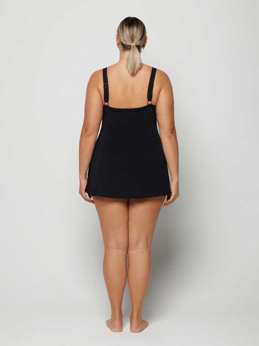 Person wearing a black and blue floral slip swim dress on a plain background