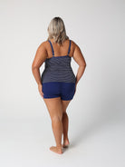 Person wearing a navy blue swimsuit with a white patterned top on a light gray background