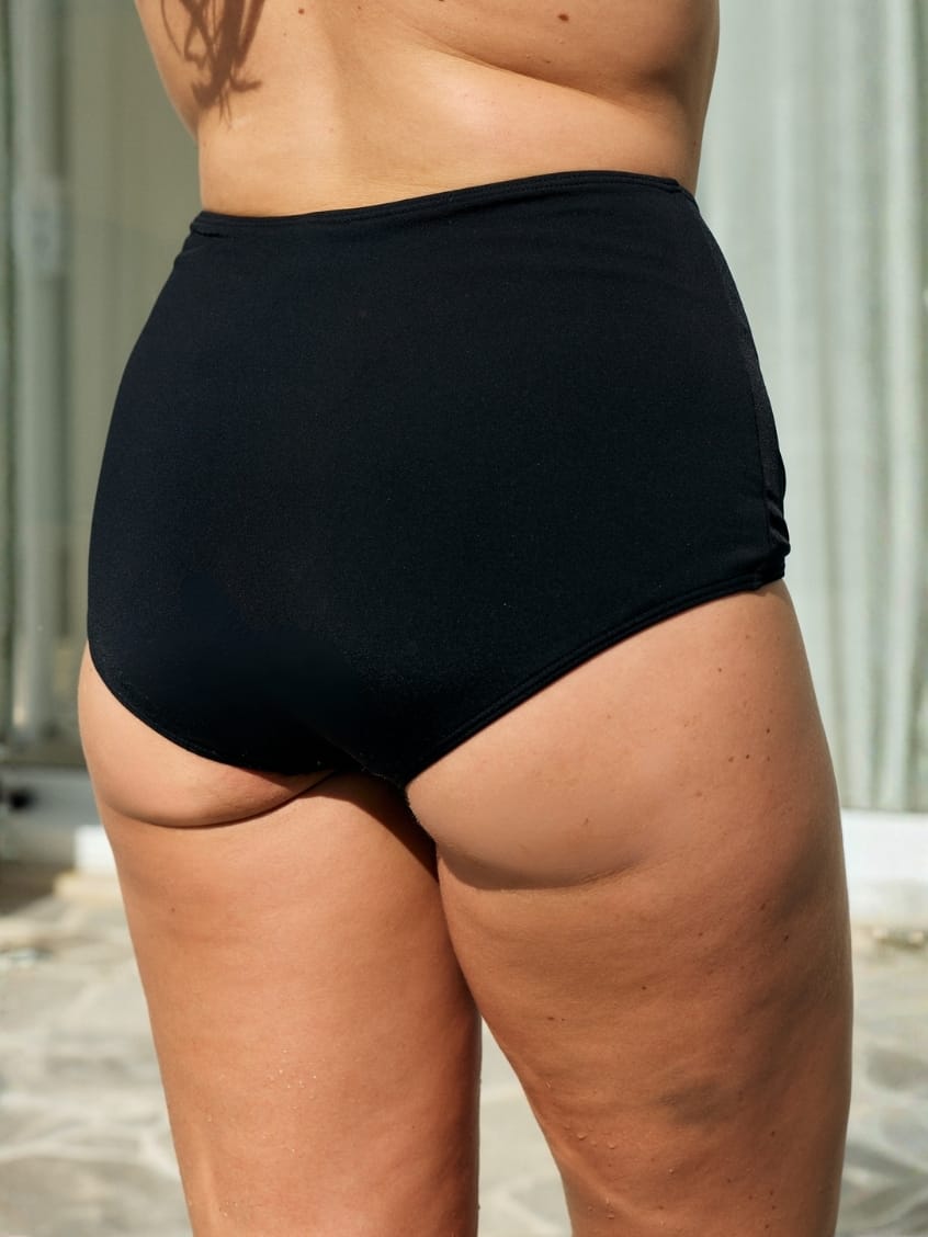 Back of model wearing a high waisted black pant in pool proof fabric