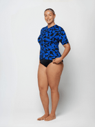 Person wearing a blue and black patterned swimsuit on a white background