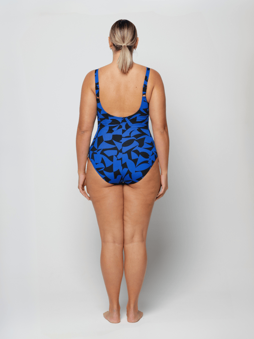 Person wearing a blue and black patterned swimsuit on a white background