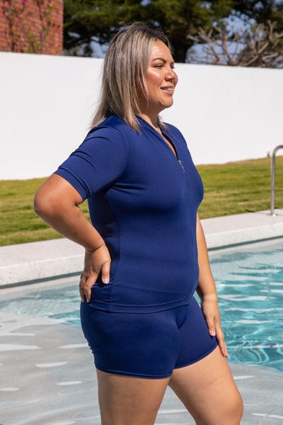 Side of model wearing a plus size chlorine resistant wet shirt in navy with zip front