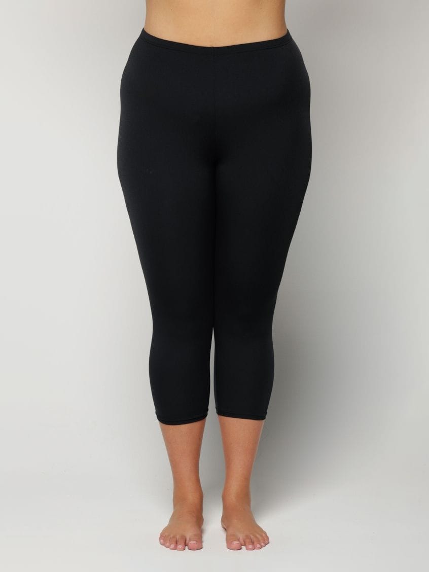 Woman wearing black capri leggings on a plain background
