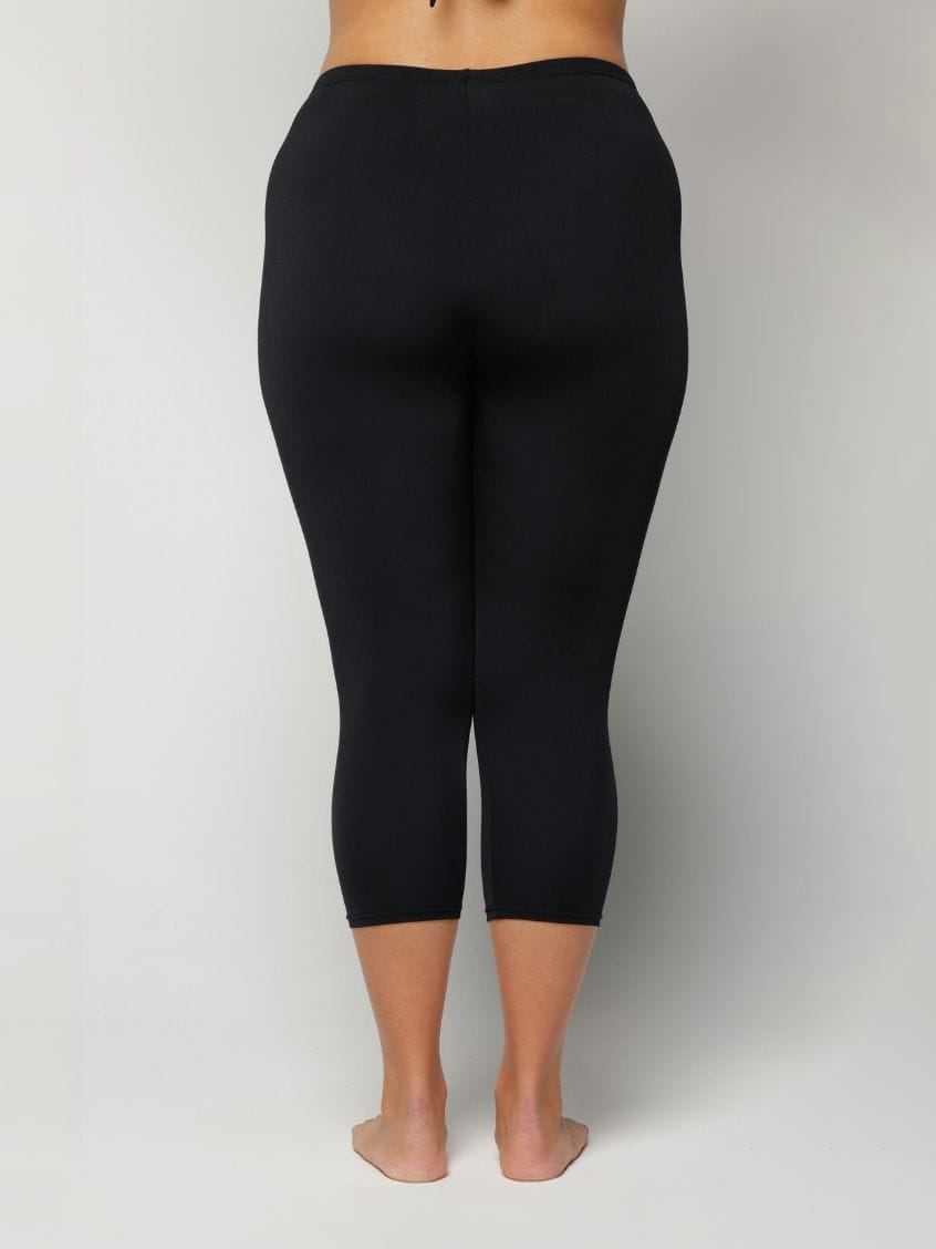Woman wearing black leggings on a plain background
