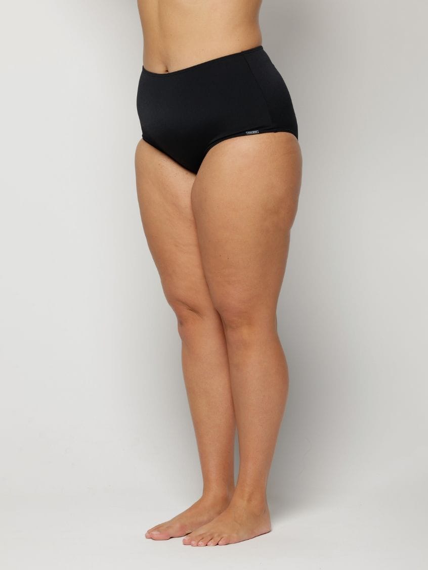 Woman wearing black high-waisted underwear on a plain background