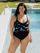 Woman wearing a black swimsuit with blue floral pattern by a pool in chlorine resistant fabric