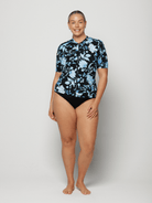 Woman wearing a black floral short sleeve rash vest in chlorine resistant