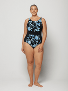 Woman wearing a black one-piece swimsuit with blue floral patterns on a white background