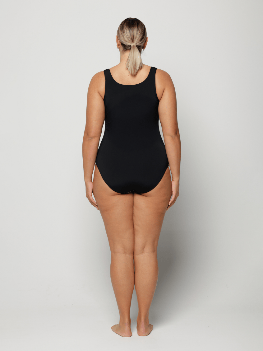 Person wearing a black and blue floral swimsuit against a white background