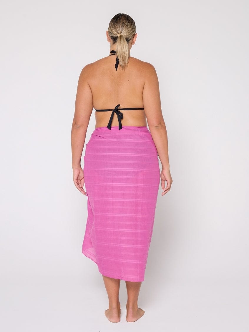 Woman wearing a pink sarong with a white background