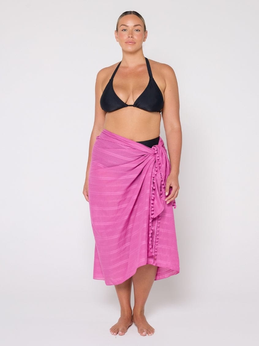 Woman wearing a black bikini and pink sarong on a white background