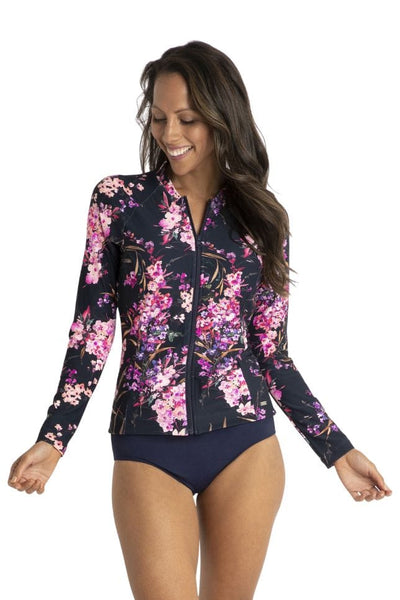 Brunette curve women wearing long sleeve rash vest with front zip in pink and purple floral detail