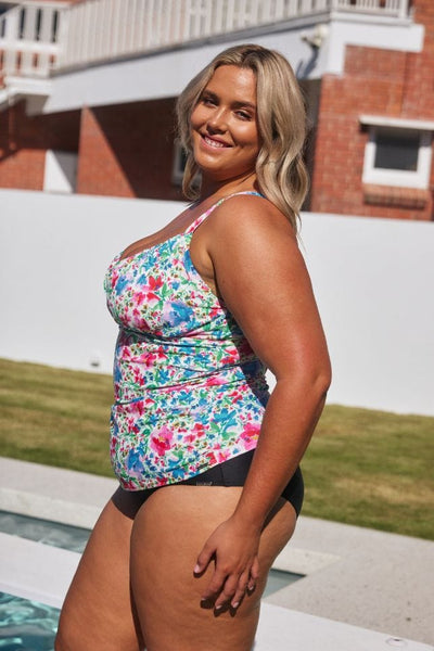 Side of model wearing plus size ruched underwire tankini top in a floral print