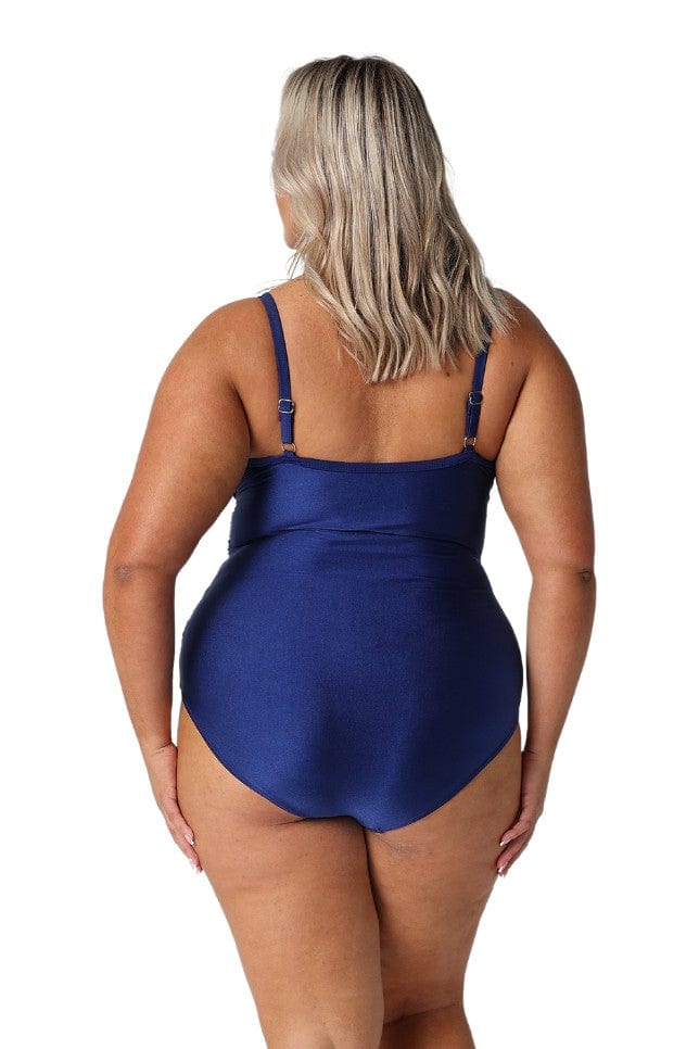 Back of model in studio wearing navy blue one piece with adjustable straps and ruching over bust area