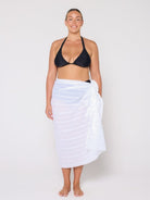 Woman wearing a black bikini and white towel on a plain background