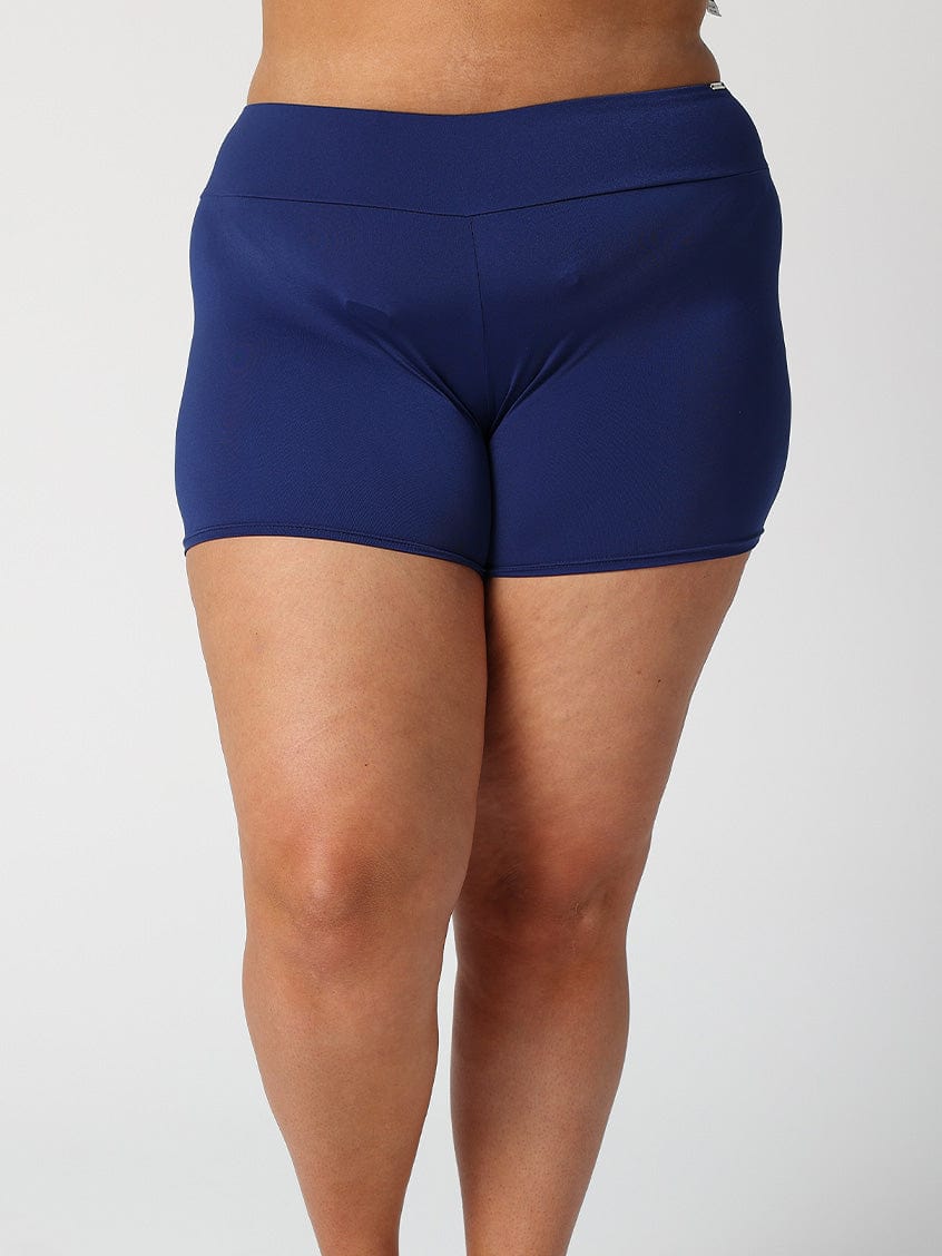 Back of model standing in pool wearing navy chlorine resistant boy leg pant for curve women