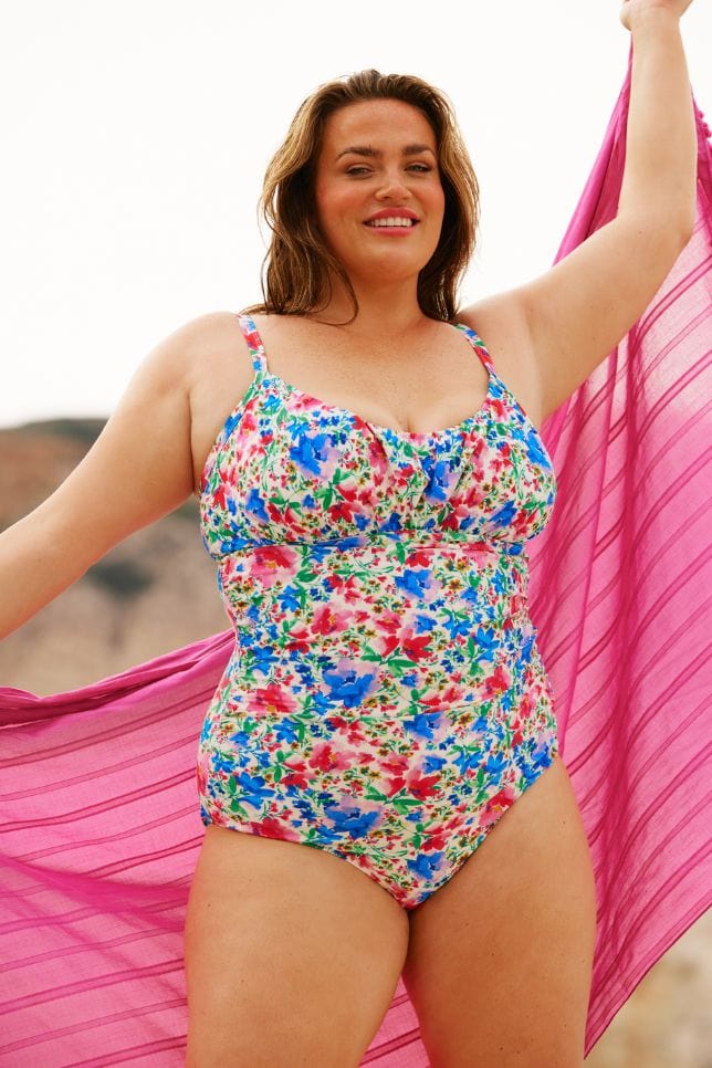 Curvy brunette model wearing an ruched underwire one piece in bright coloured floral print