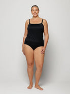 Woman wearing a black swimsuit against a white background