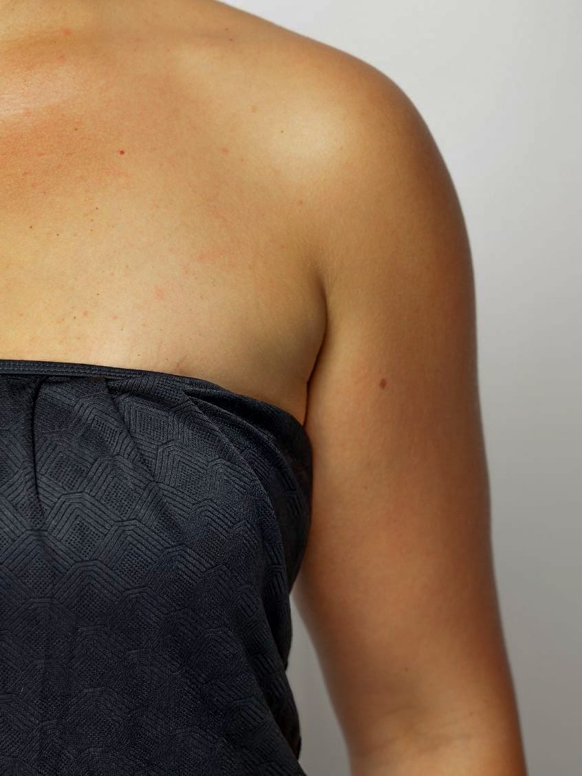 Close up of a Women wearing a strapless black swimsuit against a plain background