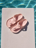 Pair of pink sandals on a diving board by a pool