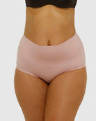 Person wearing light pink high-waisted underwear on a white background