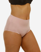 Person wearing a pair of light pink high-waisted underwear on a white background