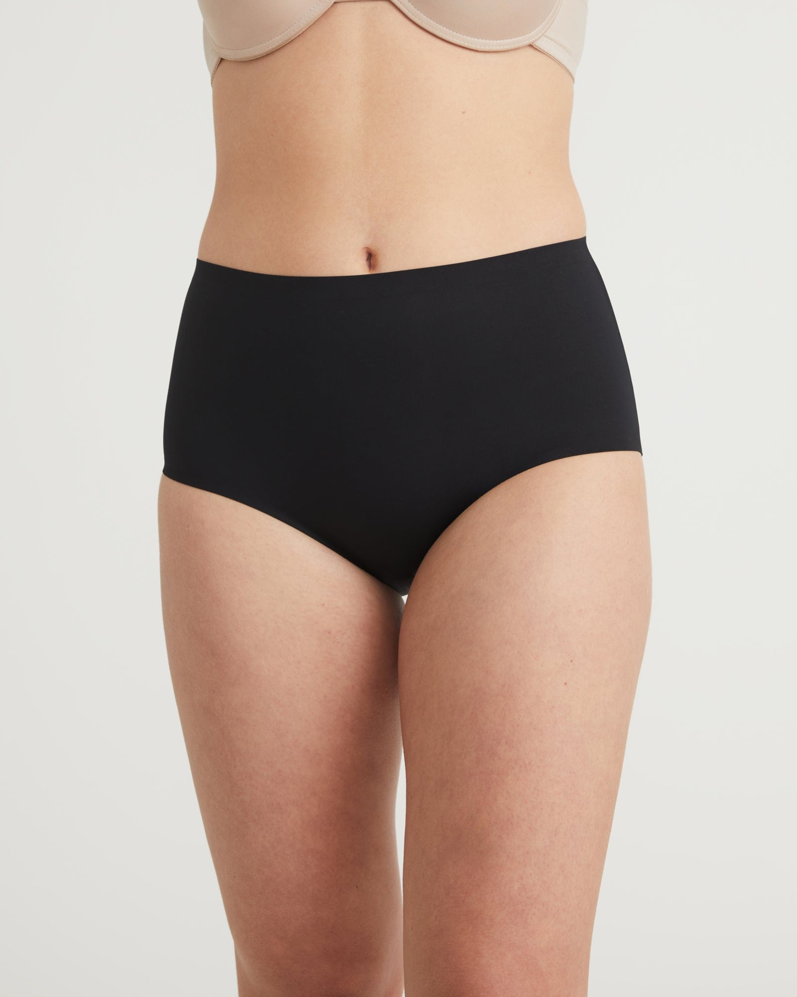 Black high-waisted underwear worn by a person on a light gray background