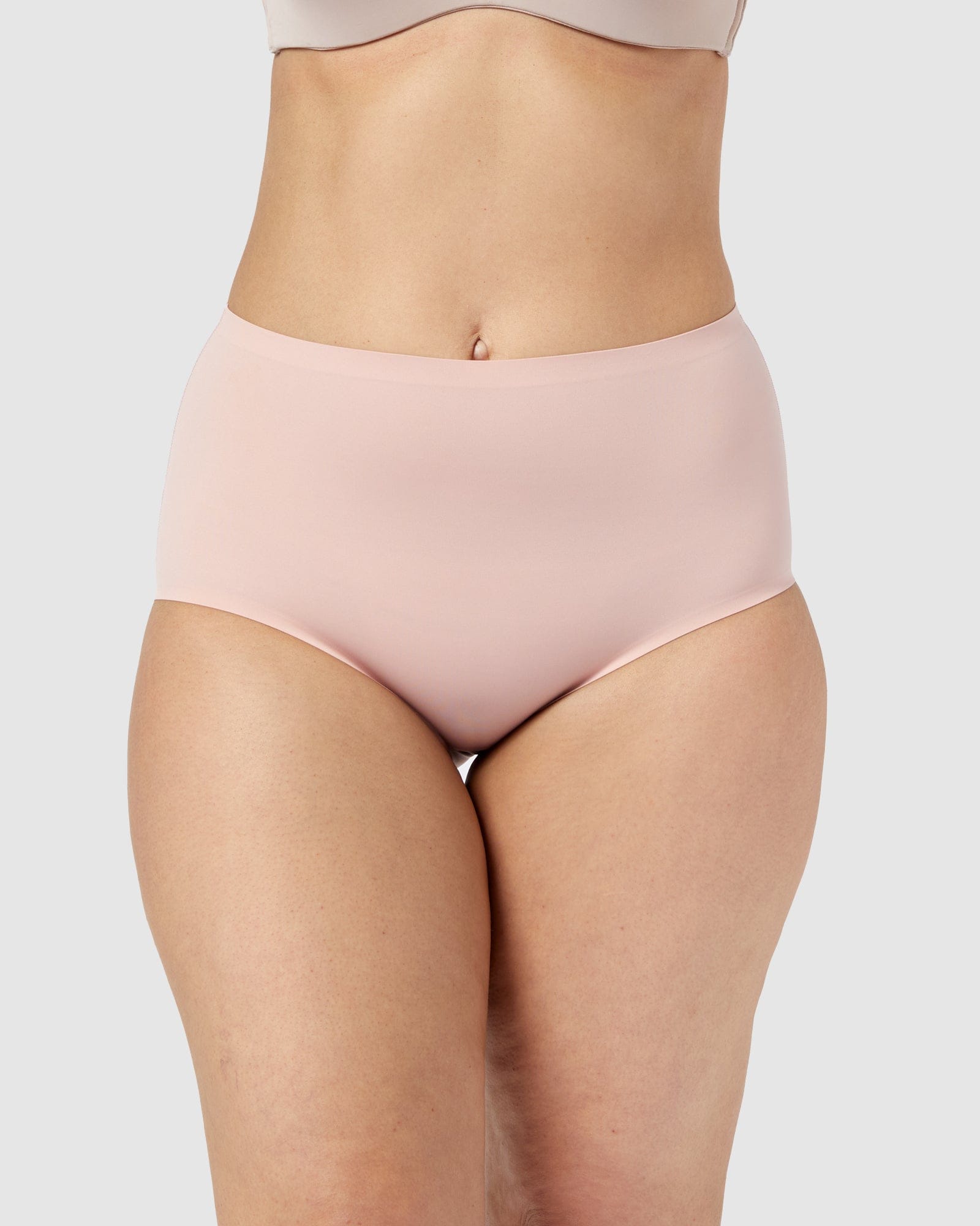 Person wearing light pink high-waisted underwear on a plain background