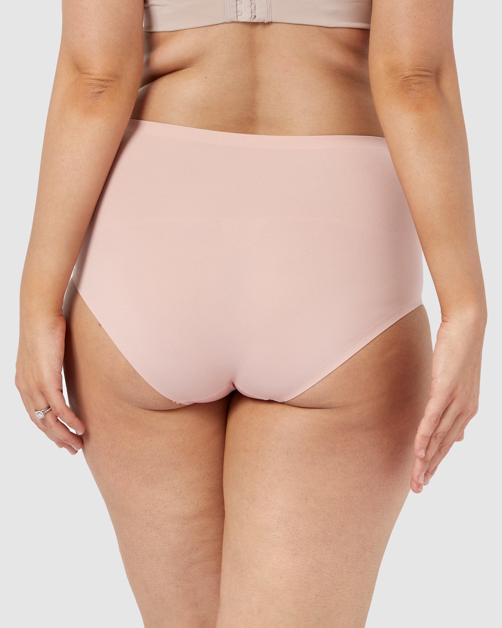 Light pink high-waisted underwear worn by a person on a plain background