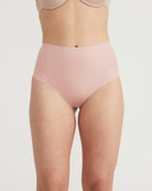 Person wearing a light pink high-waisted underwear on a plain background